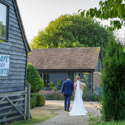 Bride & Groom walking hand in hand through gardens